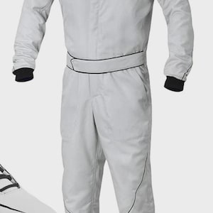 May include: Light gray racing suit with black trim and cuffs. The one-piece suit features a stand-up collar and a black belt detail. The suit is shown with white racing shoes. This racing suit is designed for motorsports.
