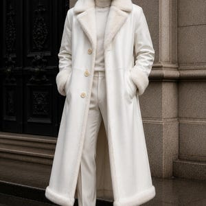 Puede incluir: Un abrigo largo blanco con cuello y pu&ntilde;os de piel sint&eacute;tica. El abrigo tiene una botonadura frontal y se combina con pantalones y botas blancos. El conjunto es completamente blanco, creando un look monocrom&aacute;tico elegante. La longitud del abrigo llega hasta los tobillos.