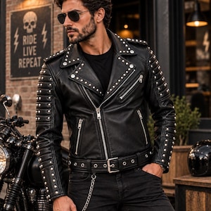 May include: A black leather motorcycle jacket featuring silver-toned metal studs along the lapels, shoulders, and sleeves. The jacket includes a front zipper closure, multiple zippered pockets, and a matching buckled belt at the waist.