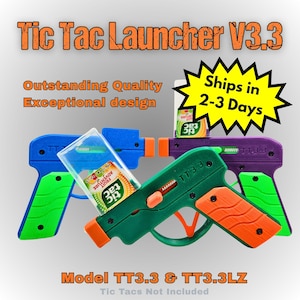 May include: A collection of toy Tic Tac Launchers in blue, green, and purple. Each launcher has orange and green accents, with the text "TT3.3" visible on the side. The image also includes the text "Tic Tac Launcher V3.3" and "Model TT3.3 & TT3.3LZ".