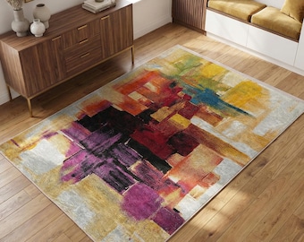 May include: An abstract area rug with a colorful geometric design. The rug features a mix of colors including yellow, purple, red, and blue. The rug is rectangular and sits on a hardwood floor.