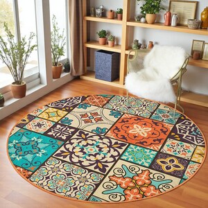 Könnte beinhalten: Ein runder Teppich mit Patchwork-Design. Der Teppich hat quadratische Muster in Türkis, Orange, Creme und Lila. Der Teppich liegt auf einem Holzboden, und der Stil ist bohème. Der Durchmesser beträgt ca. 180 cm.