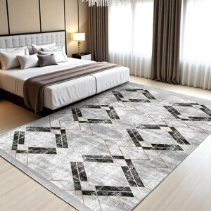 Op de afbeelding: Een grijs en wit geometrisch vloerkleed met zwarte en gouden accenten. Het vloerkleed heeft een ruitpatroon met een verweerde look.