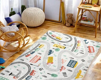 Puede incluir: Una alfombra de juego blanca y gris con un diseño de camino sinuoso. La alfombra presenta coches, camiones y edificios coloridos. La alfombra es perfecta para la sala de juegos o el dormitorio de un niño.
