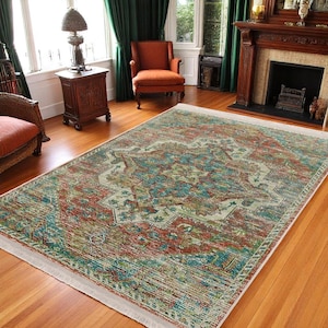 May include: A large, rectangular area rug with a distressed, vintage look. The rug features a central medallion design in shades of teal, rust, and cream, surrounded by a repeating pattern of floral motifs. The rug has a white border.