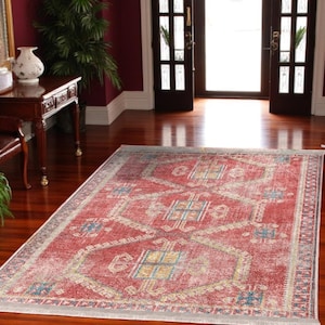 May include: A red, blue and yellow patterned area rug with a distressed look. The rug has a geometric design with a white border.