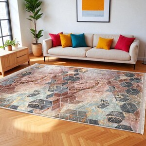 May include: A rectangular area rug with a geometric pattern in shades of brown, gray, and blue. The rug has a marble-like appearance with a white fringe border. The rug is placed on a hardwood floor.