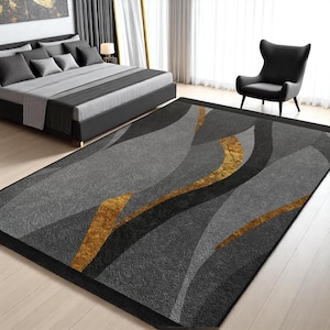 Puede incluir: Alfombra de área abstracta con fondo gris y líneas onduladas negras y doradas. La alfombra tiene un borde negro.