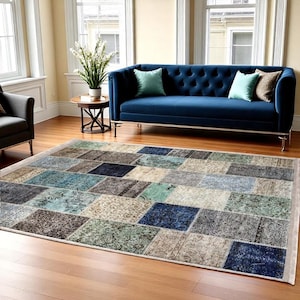Peut inclure: Un tapis bleu en patchwork avec différentes nuances de bleu, de vert et de beige. Le tapis est posé sur un sol en bois devant un canapé bleu.