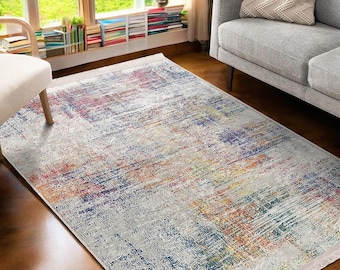 May include: A colorful abstract area rug with a white background and shades of blue, yellow, orange, and red. The rug has a distressed, faded look.