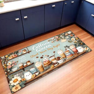 May include: A rectangular kitchen mat featuring a coffee and pastry theme. The mat has a light blue background with illustrations of coffee drinks, donuts, and the text "Caffeine Queen Start Your Day Right". Decorative floral elements frame the design.