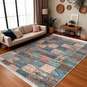 Puede incluir: Una alfombra rectangular grande con un diseño de patchwork. La alfombra presenta cuadrados en tonos de azul, rosa, beige y gris, con varios patrones. La alfombra está colocada sobre un suelo de madera en un salón.