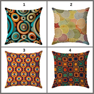 May include: Four square throw pillows with colorful geometric patterns. The pillows feature designs with circles, concentric circles, and squares in various colors, including orange, blue, and green. The pillows are arranged in a 2x2 grid.