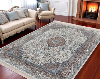 May include: A cream-coloured rug with a brown and blue floral pattern. The rug has a fringed border and is laid out on a hardwood floor.