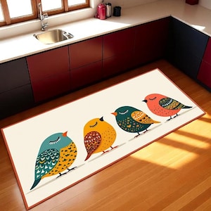 May include: A rectangular kitchen rug with a design of four colourful birds on a line. The birds are in shades of blue, yellow, orange, and teal, with detailed patterns. The rug has a cream background and a brown border, suitable for a kitchen or hallway.