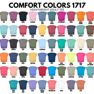 May include: A color chart of Comfort Colors 1717 heavyweight adult tees. The image displays a variety of t-shirt colors, each labeled with a unique name. The colors range from light pastels to vibrant hues, including shades of blue, pink, green, and orange.