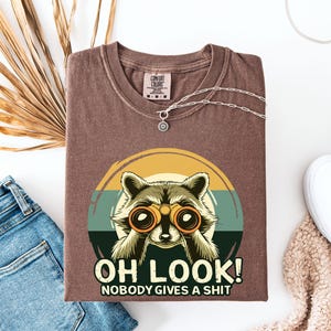 おもしろアライグマTシャツ、誰も気にしないアライグマTシャツ、おもしろミームTシャツ、皮肉Tシャツ、コンフォートカラーズ®