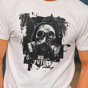 Può includere: T-shirt bianco con grafica in bianco e nero di una maschera antigas e la scritta "NO FUTURE". Il design ha un'estetica grunge e usurata. La maglietta è un classico girocollo.
