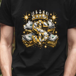 Può includere: T-shirt nero con un disegno a forma di simbolo del dollaro dorato, una corona, diamanti e pile di denaro. La grafica include stelle dorate e banconote. Il disegno è centrato sulla parte anteriore della maglietta.