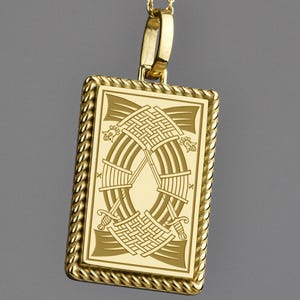 Könnte beinhalten: Eine goldfarbene Anhängerkette mit einem rechteckigen Anhänger. Der Anhänger hat ein eingraviertes Design mit einer ovalen Form und komplizierten Mustern. Die Halskette hat eine goldfarbene Kette mit kleinen Perlen.