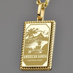 Könnte beinhalten: Goldfarbene Halskette mit rechteckigem Anhänger. Der Anhänger zeigt eine Gravur einer tropischen Szene mit dem Text "AMERICAN SAMOA NATIONAL PARK". Die Kette ist aus Gold. Der Anhänger ist ca. 2,5 cm lang.