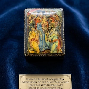 Può includere: Una scatola rettangolare in lacca nera con una scena dipinta a mano dell'Adorazione dei Magi in colori vivaci. Sotto la scatola si trova una targhetta in metallo dorato con il testo: VINTAGE PALEKH LACQUER BOX "ADORATION OF THE MAGI" MINIATURE HAND-PAINTED RUSSIAN ART GENUINE COLLECTOR'S ITEM.