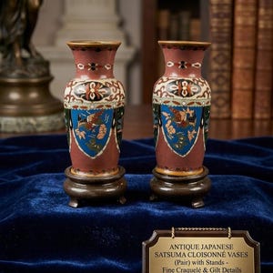 Può includere: Coppia di antichi vasi Satsuma cloisonné giapponesi con supporti. I vasi hanno uno sfondo marrone con dettagli blu, verdi e dorati. I vasi sono esposti su piccoli supporti in legno. Il testo sul cartello recita "ANTIQUE JAPANESE SATSUMA CLOISONNÉ VASES (Pair) with Stands - Fine Craquelé & Gilt Details".