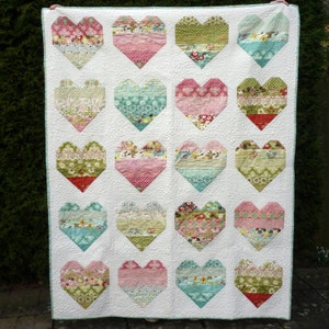Pode incluir: Um edredom branco com um design de patchwork de 16 cora&ccedil;&otilde;es. Cada cora&ccedil;&atilde;o &eacute; feito de diferentes tecidos em tons de rosa, verde, azul e branco. O edredom &eacute; feito com uma variedade de padr&otilde;es florais e geom&eacute;tricos.