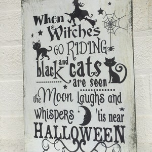 May include: A white sign with black text and images that reads "When Witches go Riding and black cats are seen the Moon laughs and whispers 'tis near HALLOWEEN".
