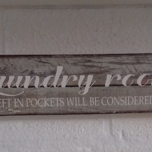 Puede incluir: Un letrero de madera rústico con letras blancas que dice "Laundry room. Change left in pockets will be considered a tip!"