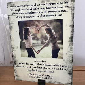 Könnte beinhalten: Ein weiß gerahmtes Foto mit einem Schwarzweißfoto von zwei Frauen, die mit ihren Händen ein Herz bilden. Das Foto hat ein Zitat über Freundschaft, das lautet: "We're not perfect and we don't pretend to be. We laugh too hard, we're way too loud and we often make complete fools of ourselves. But doing it together is what makes it fun and makes us perfect for each other. Because while a good friend knows all your best stories, a best friend has lived them with you!" Das Foto ist signiert mit "Samantha & Jayne 17th August 2020".