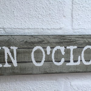 May include: A rustic wooden sign with the text "GIN O'CLOCK" in white lettering. The sign has a distressed wood look and is perfect for a bar or home decor.