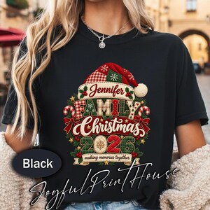 Może przedstawiać: Czarny t-shirt z świąteczną grafiką przedstawiającą czapkę Mikołaja, laski cukrowe i ostrokrzew. Napis głosi Jennifer, FAMILY, Christmas, 2026 oraz making memories together. Wzór wykorzystuje czerwono-zieloną kratę i pikowane detale.