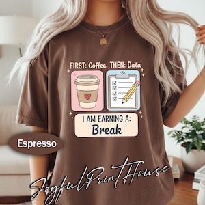Könnte beinhalten: Espressofarbenes T-Shirt mit dem Text "FIRST: Coffee THEN: Data" und "I AM EARNING A: Break". Die Grafik zeigt eine Kaffeetasse mit Herz und eine Checkliste mit Bleistift. Das Shirt stammt von Joyful Print House.