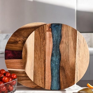 Könnte beinhalten: Zwei runde Holz-Servierbretter mit einem dekorativen Harzeinleger. Ein Brett hat einen blauen Harzeinleger und das andere einen violetten Harzeinleger.