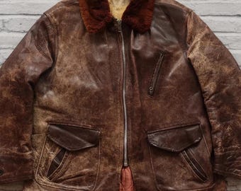 May include: A brown leather jacket with a fur collar and multiple pockets. The jacket has a distressed look and is worn.