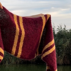 Könnte beinhalten: Ein gestrickter Schal in den Farben Rotbraun und Gold mit langen Fransen.