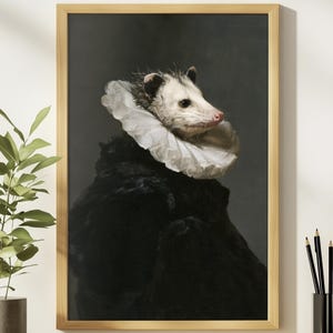May include: A framed wall art print featuring a portrait of an opossum wearing a large, white, ruffled Elizabethan-style collar and a dark, textured black garment against a solid, muted gray background, encased in a light-toned wooden frame.