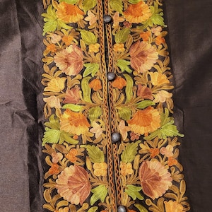 May include: A brown silk jacket featuring intricate floral embroidery in shades of orange, green, and brown. The jacket has a mandarin collar and a button fastening.