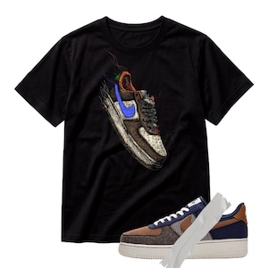 Może przedstawiać: Czarny t-shirt z krótkim rękawem z grafiką przedstawiającą sneakersa z niebieskim logo i postrzępionymi nitkami. Pod koszulką znajduje się fizyczny but sportowy z brązową, granatową i kraciastą cholewką oraz białą gumową podeszwą.