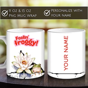 May include: White ceramic mug featuring the phrase "Feelin' Froggy!" in red and pink, with a frog and water lily design. The other side of the mug has the text "YOUR NAME" in red. The mug is available in 11 oz and 15 oz sizes.