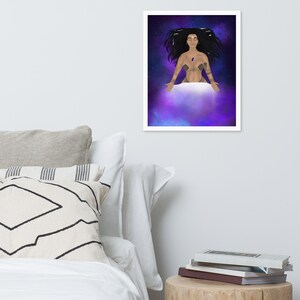 May include: A framed art print showing a celestial illustration. The artwork depicts a figure with long black hair, adorned with tattoos and a gemstone, floating in a purple and blue nebula. The print is displayed on a white wall above a bed with pillows.