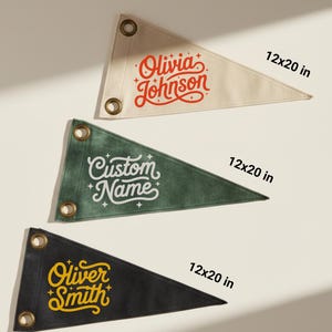 Peut inclure: Trois fanions triangulaires, chacun de 30x51 cm, avec des œillets. L'un est de couleur crème avec "Olivia Johnson" en script rouge. Un autre est vert avec "Custom Name" en blanc. Le dernier est noir avec "Oliver Smith" en jaune.