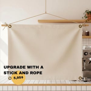 May include: A rectangular off-white canvas banner featuring metal grommets in each corner, suspended from a wooden rod by a thin rope. The banner displays the black text UPGRADE WITH A STICK AND ROPE and a yellow circle containing the text 5,95$.