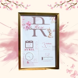 Può includere: Una stampa incorniciata con bordo dorato, con il nome "Rose" in un carattere decorativo. La stampa include un'illustrazione di coniglietto, elementi floreali e dettagli della nascita: data, ora, peso (3,735 kg) e lunghezza (52 cm).