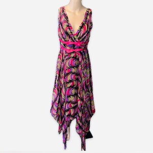 May include: A sleeveless, V-neck dress with a vibrant, abstract pattern in shades of pink, purple, green, and black. The dress features a bright pink ribbon belt and a handkerchief hemline. The dress is displayed on a mannequin.