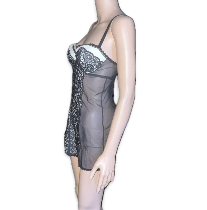May include: Black and white lingerie set. The set features a sheer black fabric with a white bust and black lace detailing. The straps are black and the garment is designed to be worn as a nightgown or undergarment.