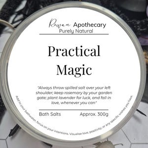 Op de afbeelding: Witte pot met een zwart etiket waarop "Rewan Apothecary Purely Natural Practical Magic" staat. Het etiket bevat ook de tekst "Always throw spilled salt over your left shoulder; keep rosemary by your garden gate; plant lavender for luck, and fall in love, whenever you can." en "Bath Salts Approx. 300g".