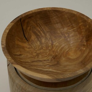Może przedstawiać: Drewniana miska z naturalnym wzorem słoj&oacute;w drewna. Miska wykonana jest z jasnobrązowego drewna i ma gładką, zaokrągloną powierzchnię.