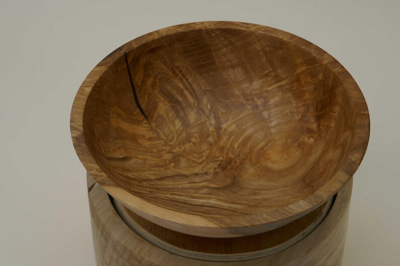 Może przedstawiać: Drewniana miska z naturalnym wzorem słoj&oacute;w drewna. Miska wykonana jest z jasnobrązowego drewna i ma gładką, zaokrągloną powierzchnię.